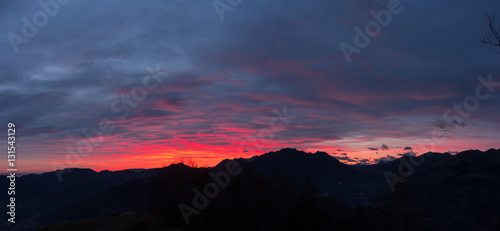 Fiery sunset from mountain pick in a cloudy evening. Fall season. Orobie mountains. Italian Alps.