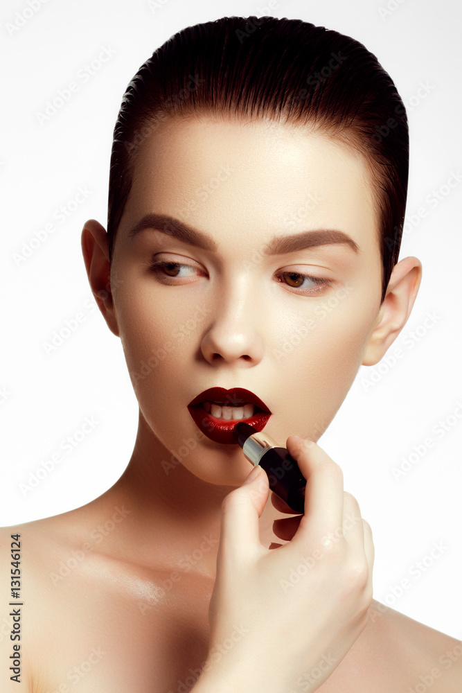 Fashion and beauty. Beautiful young woman with wine lipstick. Brunette model with dark red colored pomade. Beautiful model girl applying lipstick Fashion and beauty. Beautiful young woman with wine lipstick. Brunette model with dark red colored pomade. Beautiful model girl applying lipstick