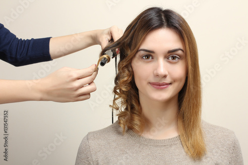 Hairdresser turns girl's hair on curling.