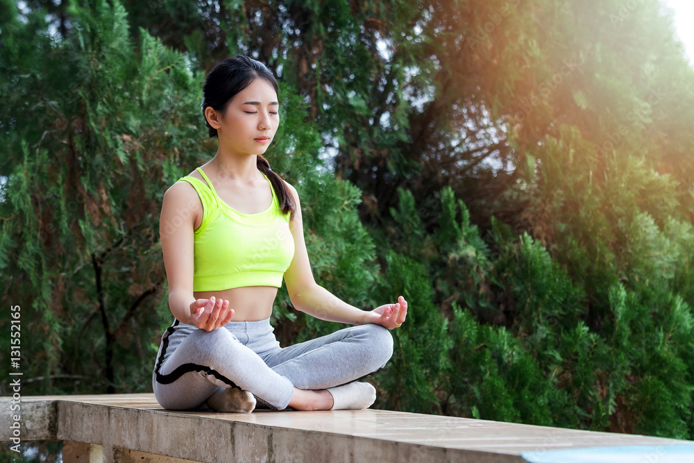 young woman in sportswear meditating while sitting in lotus pose young woman in sportswear meditating while sitting in lotus pose