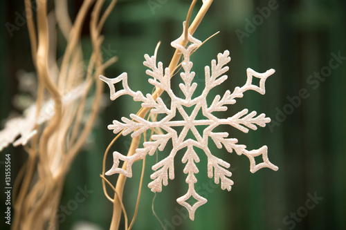 Светло-бежевая снежинка на оголенных бежевых веточках веточках на оливковом фоне