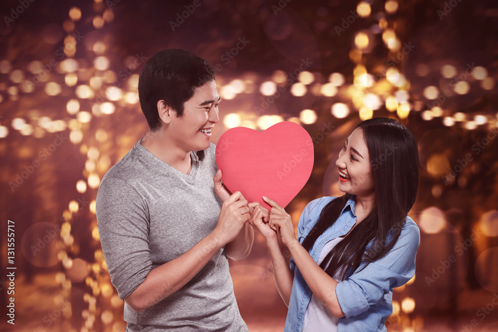 Romantic asian couple holding red heart shape