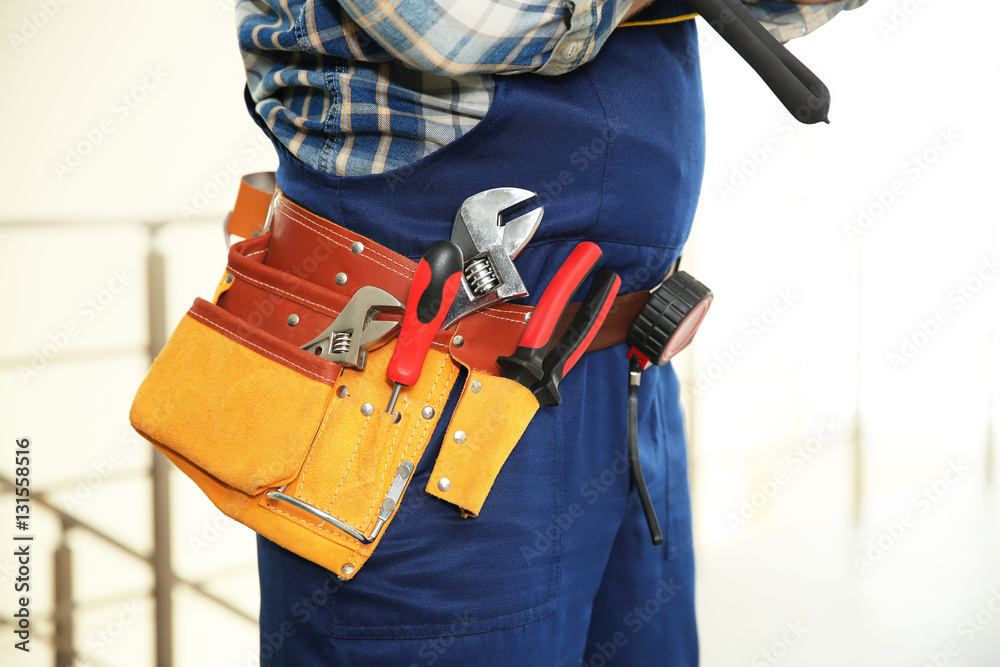 Worker with tools belt on light background, close up view Worker with tools belt on light background, close up view