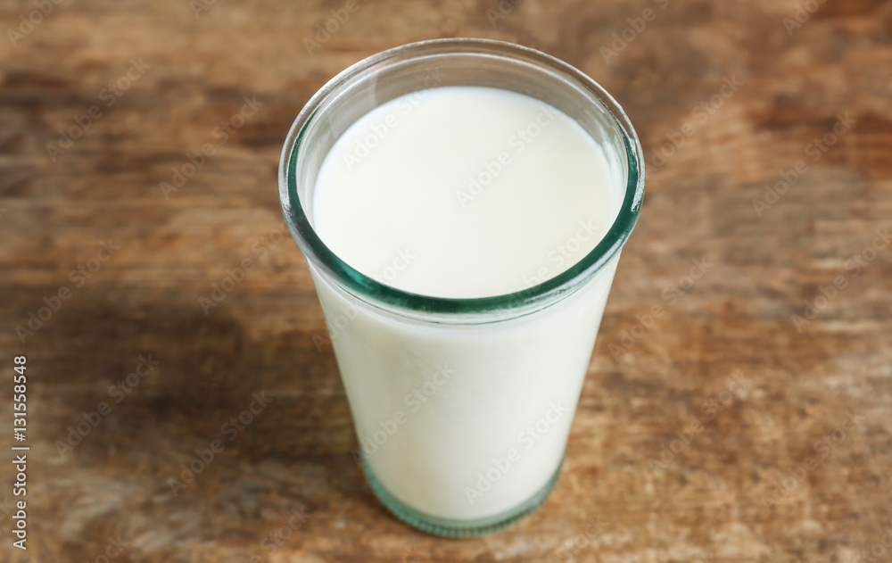 Glass of milk on blurred wooden background, closeup Glass of milk on blurred wooden background, closeup
