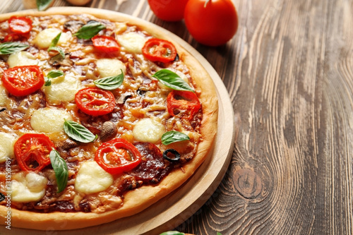 Fresh pizza with tomatoes, cheese and mushrooms on wooden background