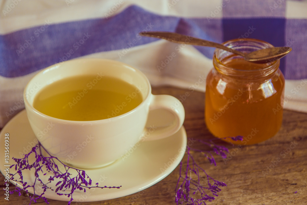 Green tea in a white cup and jar of honey with spoon and blue ki Green tea in a white cup and jar of honey with spoon and blue ki