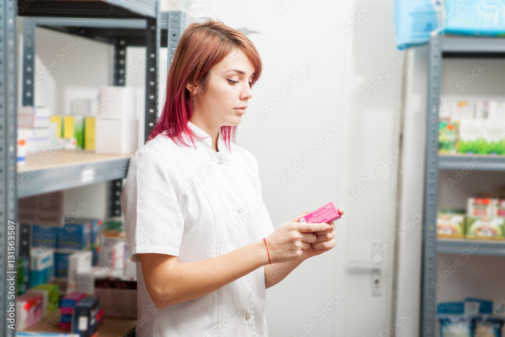 Pharmacist in the warehouse looking at box with pills