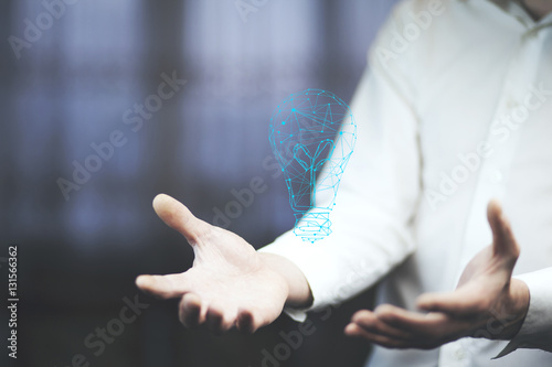male hand is showing flying virtual light bulb. © ARAMYAN