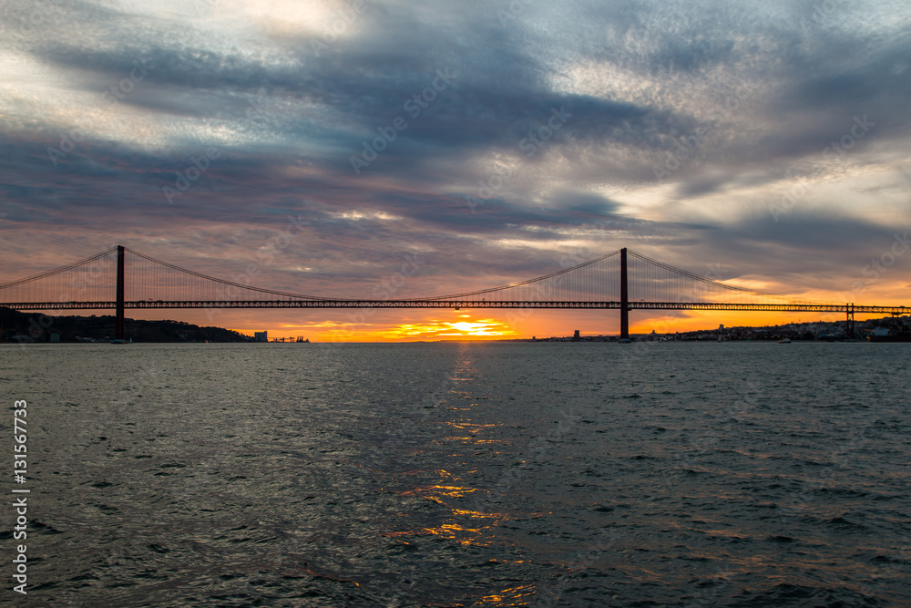 Sunset sky above Tagus River, Bridge April 25 Lisbon and port at from ship,  Portugal. Stock Photo