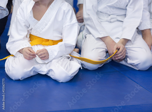 Children in kimono sitting on tatami on martial arts training seminar