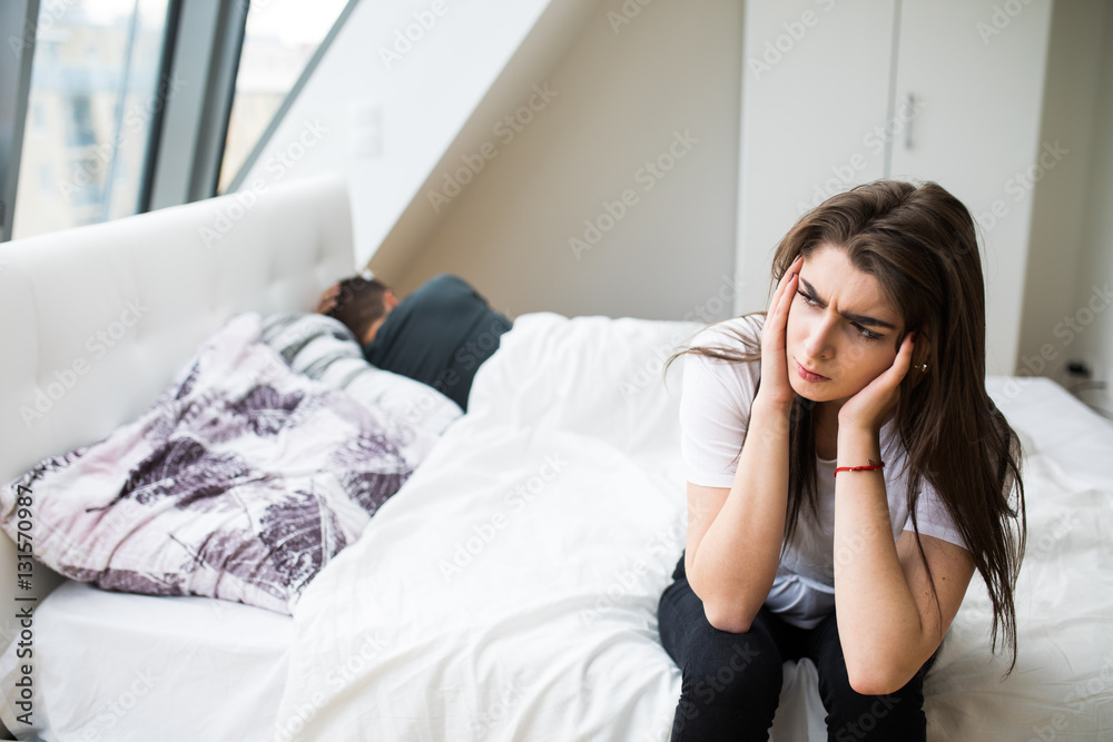 Portrait of unhappy young heterosexual couple in bedroom Portrait of unhappy young heterosexual couple in bedroom