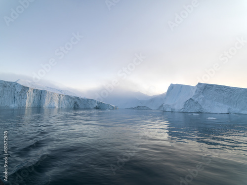 Arctic Icebergs Greenland in the arctic sea. You can easily see that iceberg is over the water surface, and below the water surface. Sometimes unbelievable that 90% of an iceberg is under water