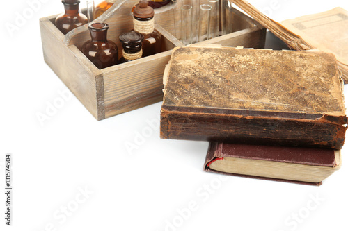 Vintage bottles in wooden box and old books isolated on white