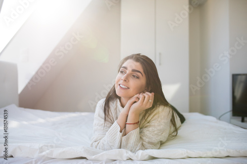Happy woman lying on the bed and waking up in the morning