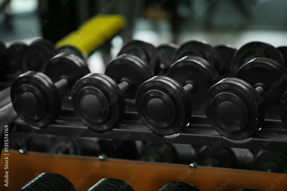 Rack with different dumbbells in gym, close up Rack with different dumbbells in gym, close up