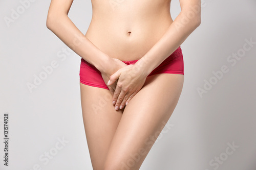 Close up view of young woman on grey background. Gynecology concept © Africa Studio