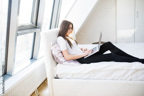 Young woman using laptop in bed