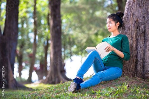 Beautiful young asian woman sitting and reading book in a park