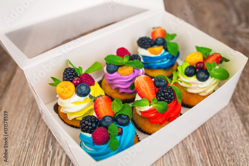Colorful cupcakes with berries in a gift box.