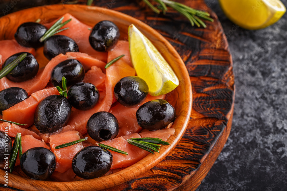 Salmon with olives and lime on a wooden board.