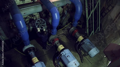 A woman twists the industrial valve on pumping station, she twirls it
