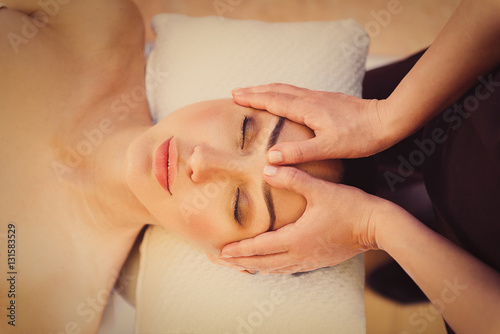 Professional masseuse massaging female face