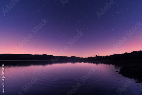 Ripples on a lake at sunrise with star filled purple sky
