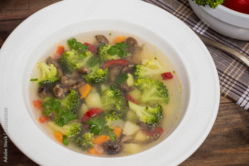 Vegetable soup with broccoli, mushrooms and herbs. Wooden background. Top view. Close-up