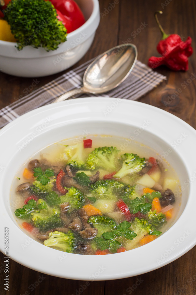 Vegetable soup with broccoli, mushrooms and herbs. Wooden background. Top view. Close-up Vegetable soup with broccoli, mushrooms and herbs. Wooden background. Top view. Close-up