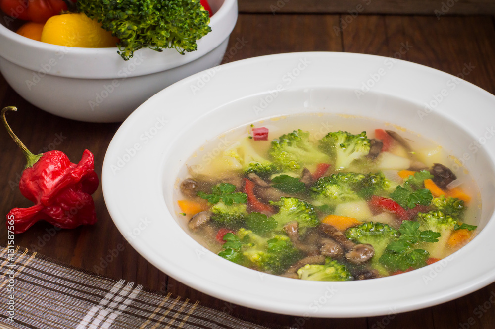 Vegetable soup with broccoli, mushrooms and herbs. Wooden background. Top view. Close-up Vegetable soup with broccoli, mushrooms and herbs. Wooden background. Top view. Close-up