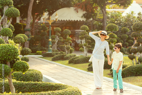 Canvas Print Young mother and her little son walking in Green bonsai trees gardens in Wat Aru