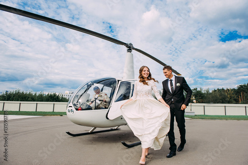 Happy beautiful newlyweds near the helicopter