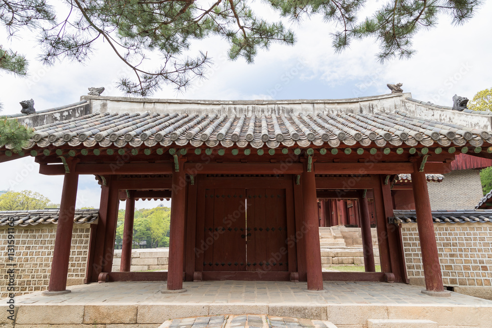 Wooden gate and stone wall next to the Jeongjeon - the main hall of the Jongmyo Shrine in Seoul, South Korea, viewed from the front.