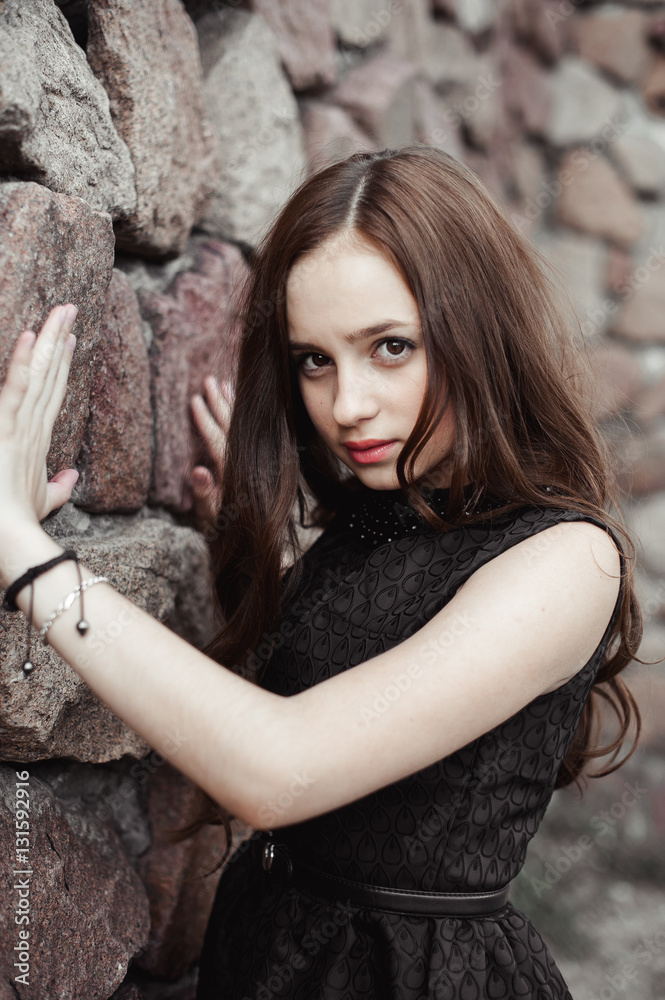 Fototapeta premium beautiful sad young woman on a stone wall background