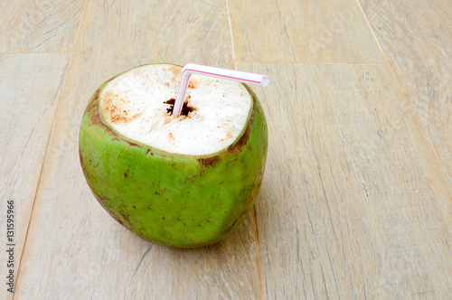 Coconut with a white and red straw isolated on a wood surface
