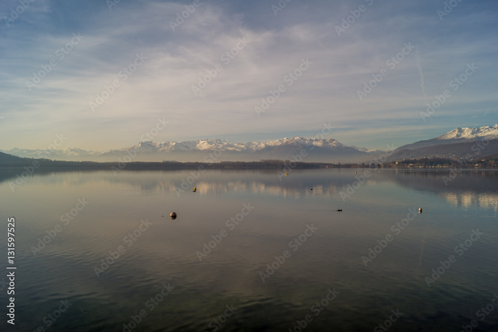 landscape on lake with blue sky and clouds. Mountains on background