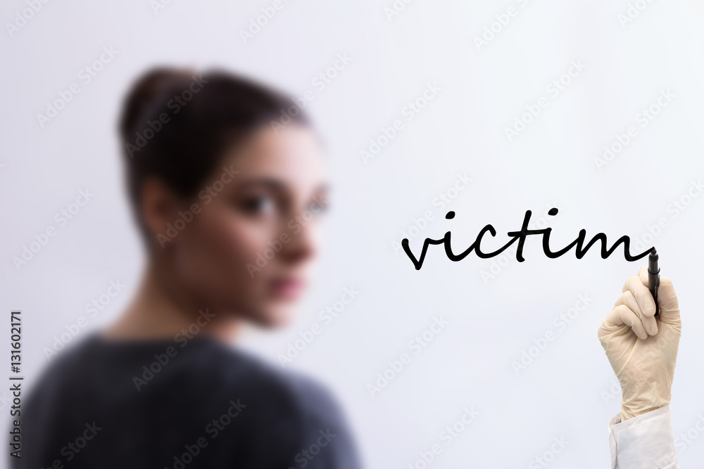 Blurred girl in background and hand writing victim Blurred girl in background and hand writing victim