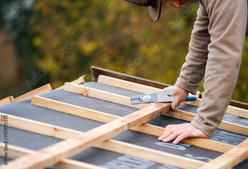 construction worker on a renovation roof covering it with tiles