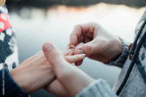 Picture of man putting engagement silver ring on woman hand, out