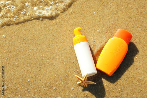 Lotion bottles with starfish on beach sand