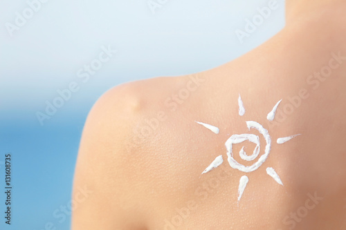 Woman with sun protective lotion in sun shape on shoulder