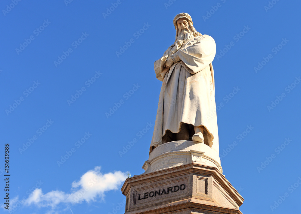 Fototapeta premium statue of leonardo da vinci against blue sky with a fluffly white cloud on e bright spring day in milan, italy