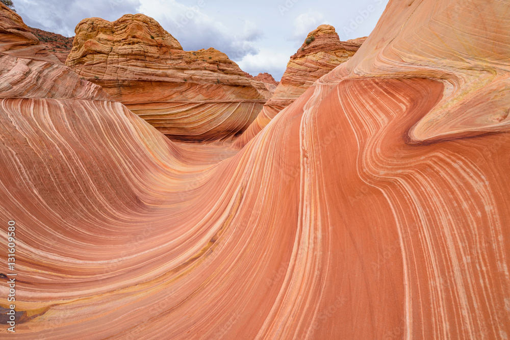 Dark clouds coming over colorful and swirling sandstone rock formations at The Wave - a dramatic erosional sandstone rock formation located in North Coyote Buttes area at Arizona-Utah border.