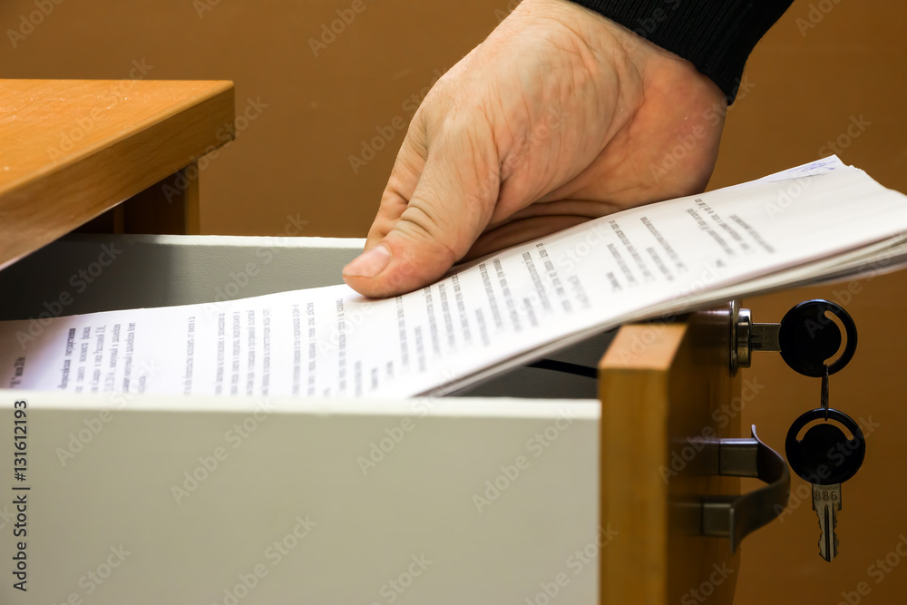 Man puts or takes the documents from the drawer - obrazy, fototapety, plakaty 