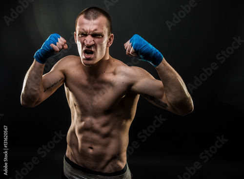 Muscular man standing with mouth opened holding fists up. Studio shot. © zamuruev