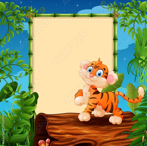 Fototapeta Naklejka Na Ścianę i Meble -  Cartoon tiger on hollow log near the empty framed signboard 