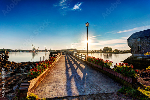 Sun rises over the Piscataqua River and the Portsmouth Navy Yard as seen from Prescott Park, Portsmouth, NH photo