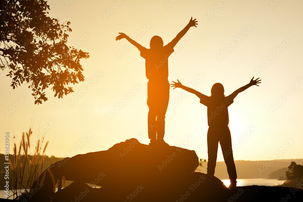 Silhouette of happy women on the rock near the river