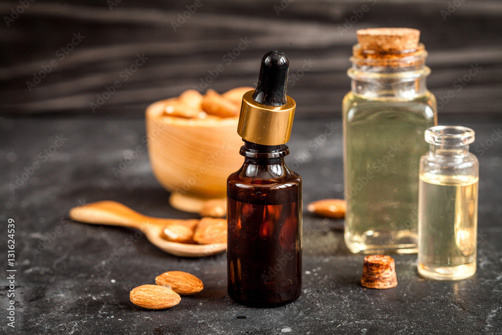 cosmetic almond oil in glass bottle on dark wooden background