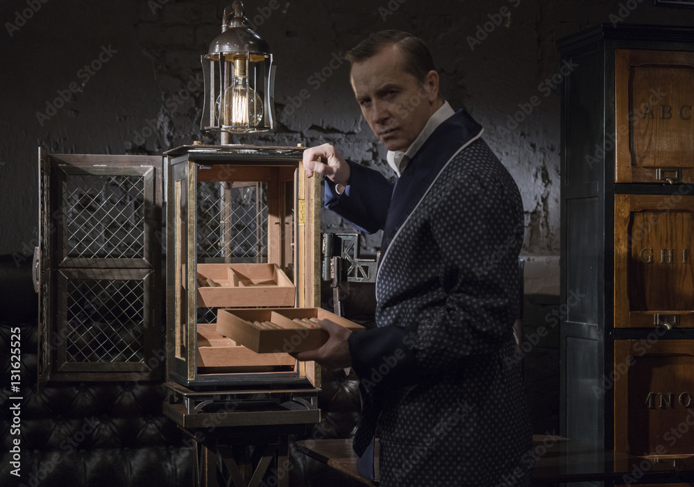 Handsome man in elegant suit smoking a Cuban cigar and drinking alcohol Handsome man in elegant suit smoking a Cuban cigar and drinking alcohol